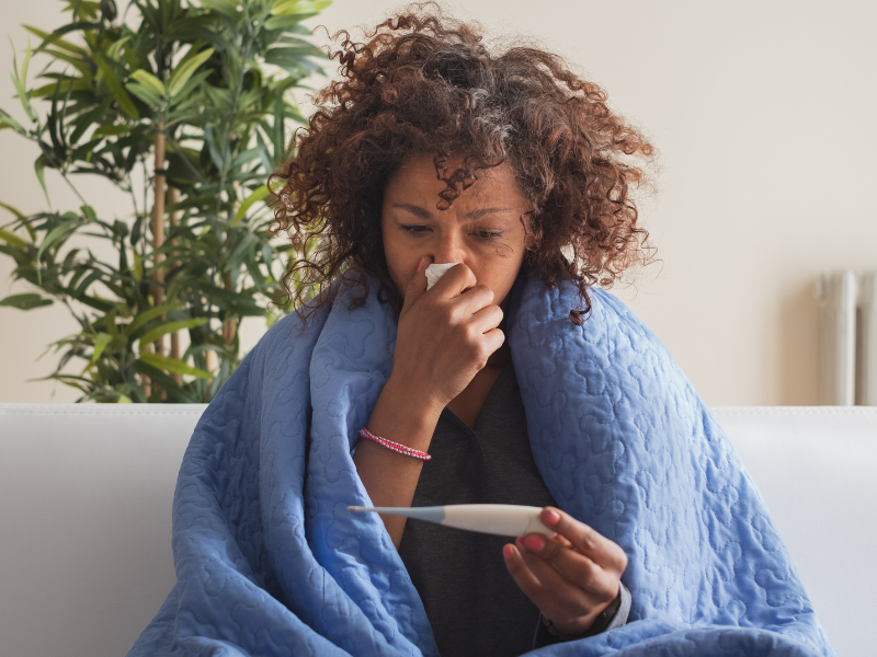 Mujer enferma con virus respiratorio monitorea su temperatura.