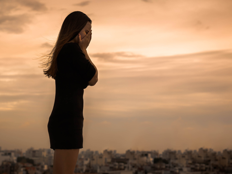 Persona visiblemente afectada con manos en la cara y en depresión